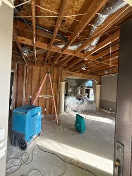 Ceiling and walls opened to framing, two dehumidifiers on the load